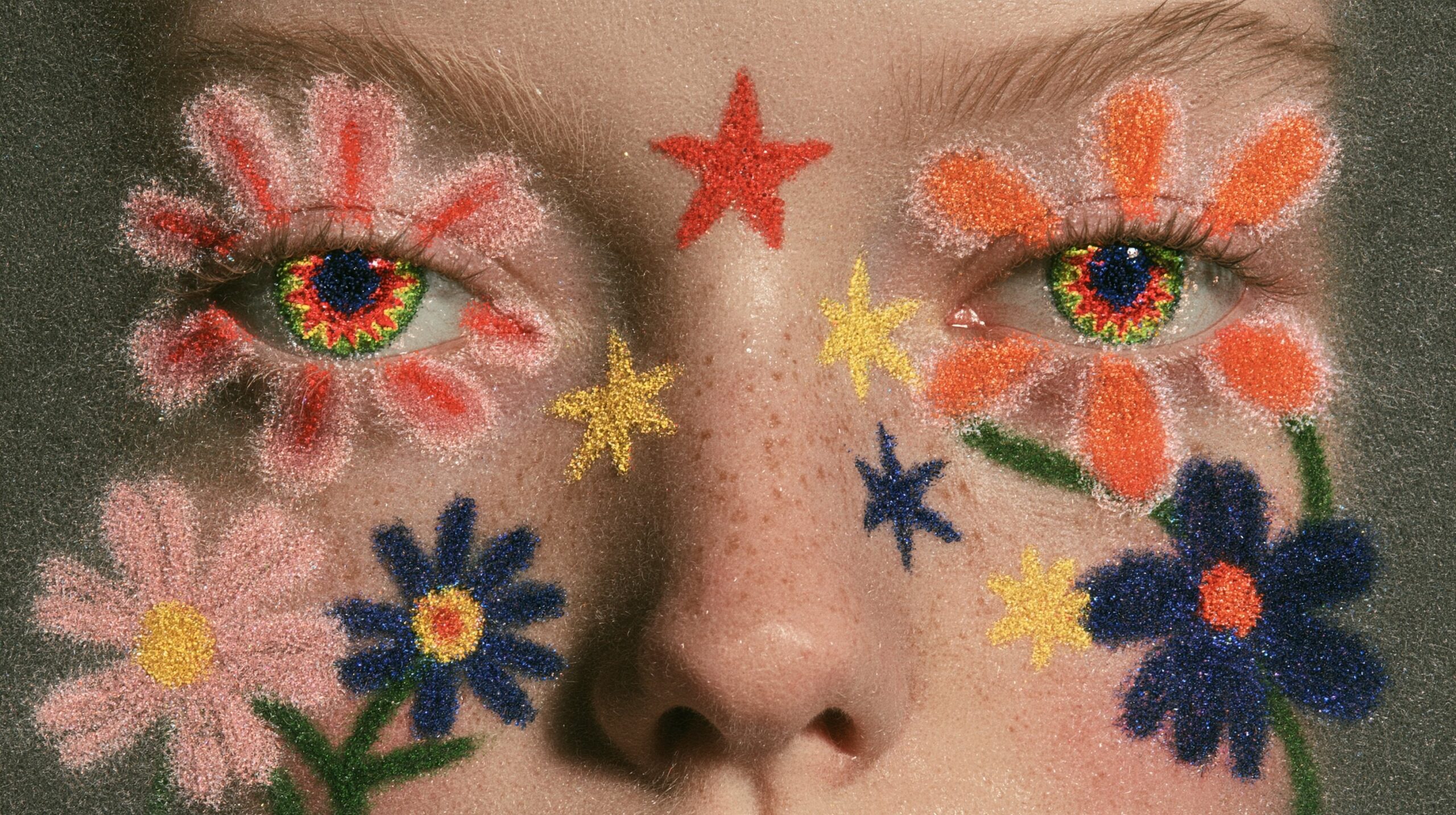 Volto con fiori e stelle disegnati in glitter intorno agli occhi